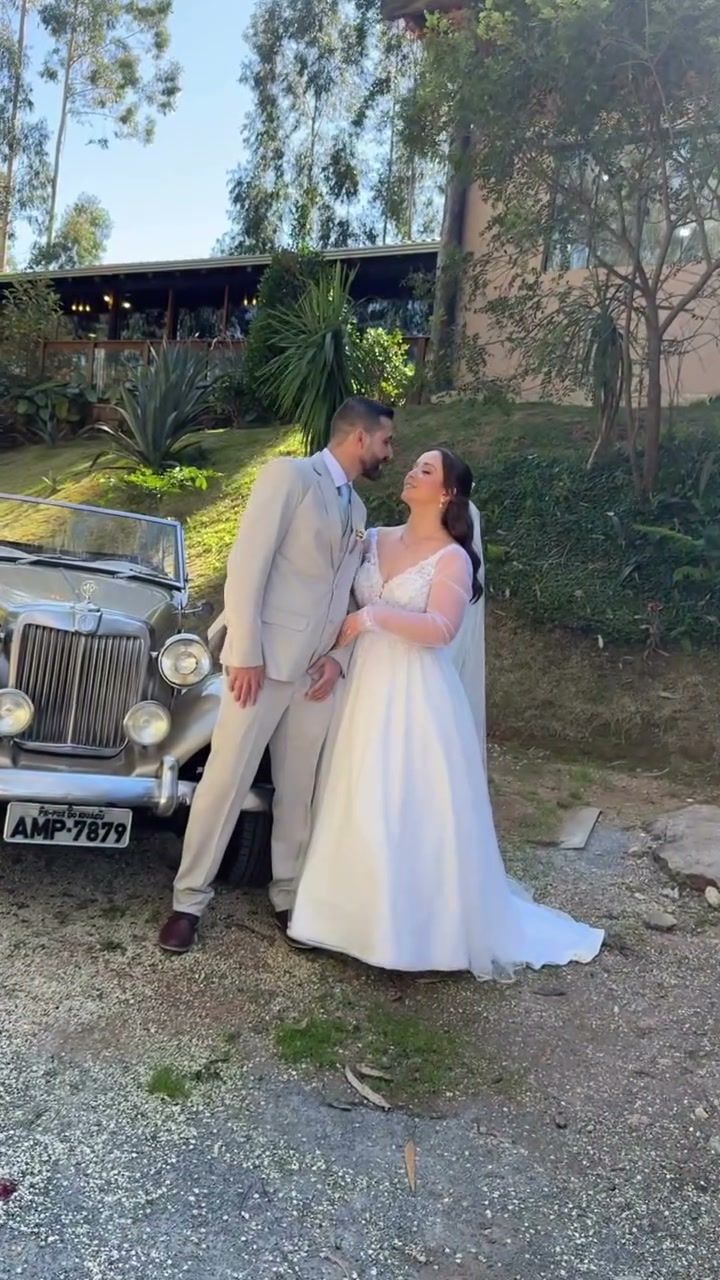 Noivos posando ao lado de carro antigo